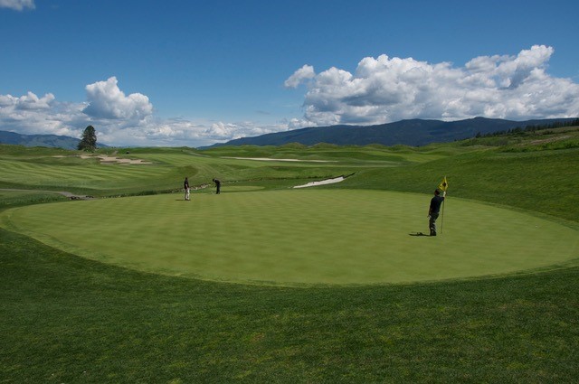 Under blue skies at Predator Ridge in B.C.’s Okanagan region, the author tends the flag, in the pre-COVID days, when you were allowed to tend the flag, and the skies were indeed blue, and crossing the border to get to Predator from the U.S. was not a problem. 